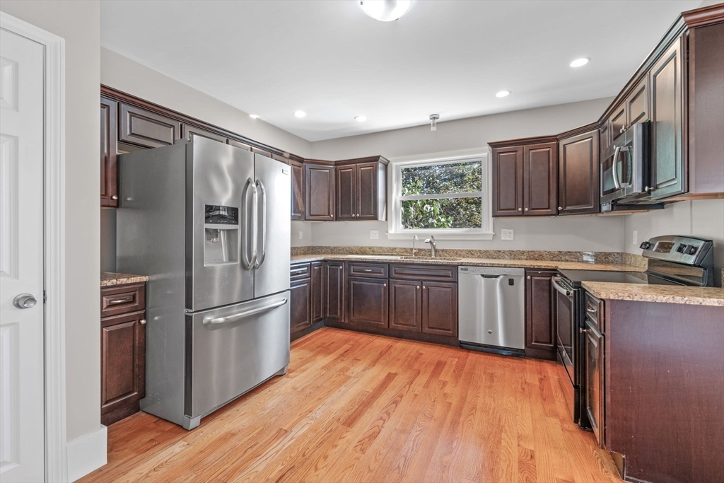 21 Lyman Street Beverly, MA 01915 - Photo 11 of 33 a kitchen with stainless steel appliances granite countertop a refrigerator a sink dishwasher a stove and white countertops with wooden floor