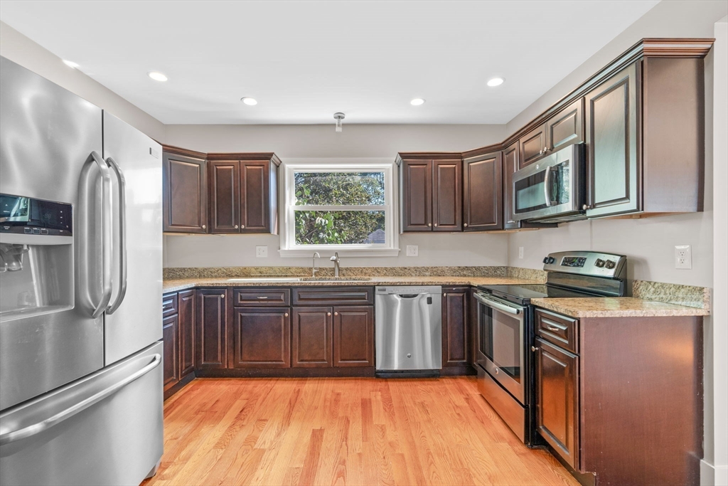 21 Lyman Street Beverly, MA 01915 - Photo 10 of 33 a large kitchen with stainless steel appliances granite countertop a stove top oven a refrigerator and a sink