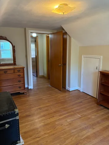 a view of an empty room with closet and wooden floor