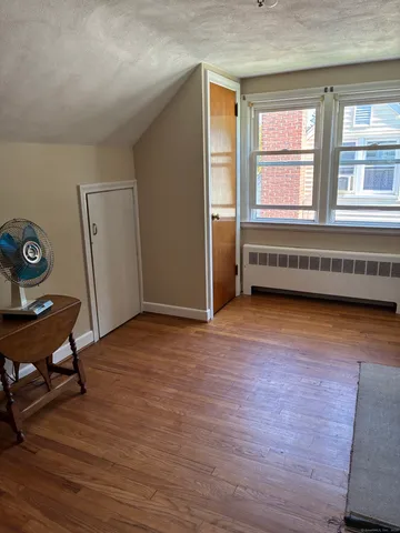 a view of an empty room with a window and wooden floor