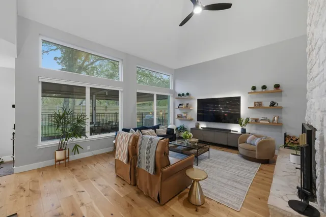 a living room with furniture floor to ceiling window hardwood floor and a flat screen tv