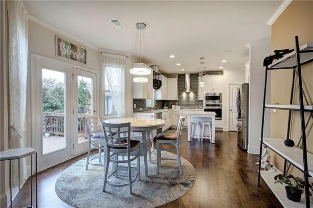 a dining room with stainless steel appliances granite countertop a table chairs and a chandelier
