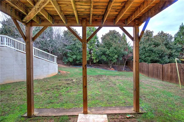 a view of a backyard with large trees and wooden fence