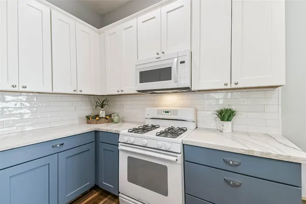 a kitchen with granite countertop white cabinets and white appliances