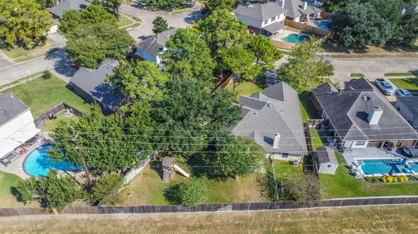 an aerial view of residential houses with outdoor space and trees