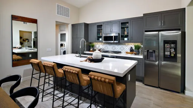 a kitchen with stainless steel appliances kitchen island granite countertop a dining table chairs refrigerator and sink