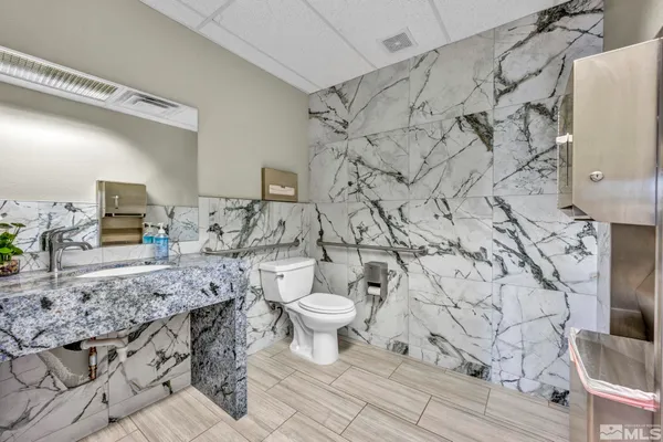 a bathroom with a granite countertop toilet and a sink