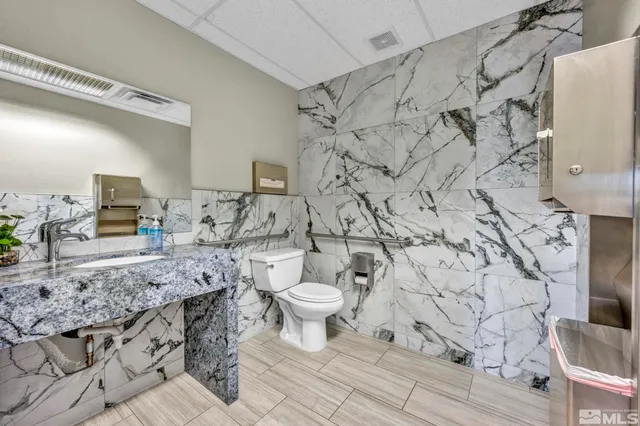 a bathroom with a granite countertop toilet and a sink