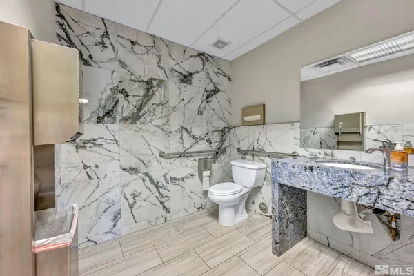a bathroom with a granite countertop toilet and a sink