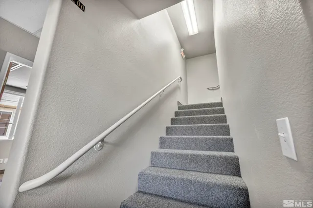 a view of staircase with white walls and white door