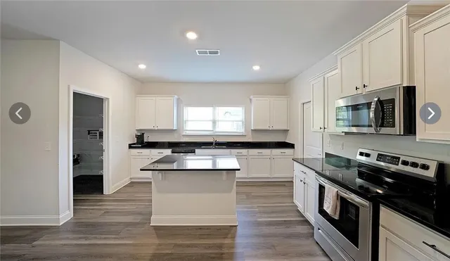 a kitchen with stainless steel appliances kitchen island granite countertop a stove a sink and a refrigerator