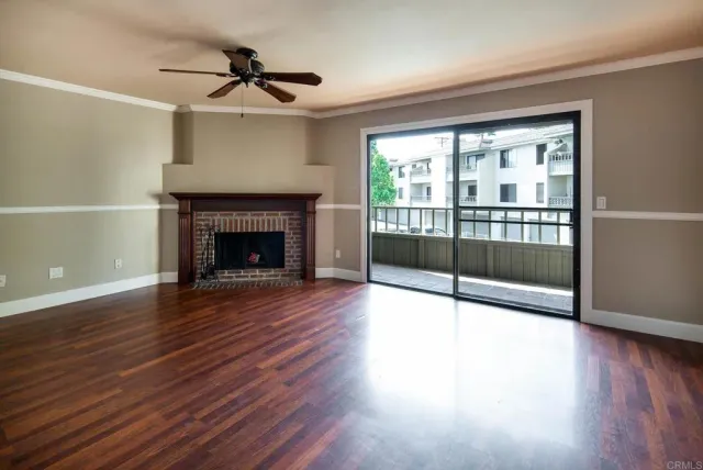 a view of an empty room with wooden floor and a fireplace