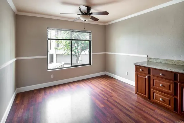an empty room with wooden floor fan and windows
