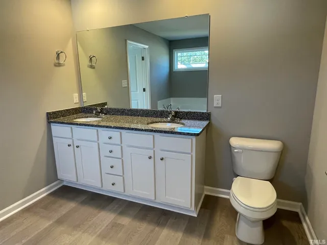 a bathroom with a granite countertop toilet sink and mirror