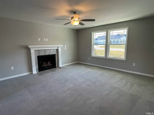 an empty room with chandelier fan and windows