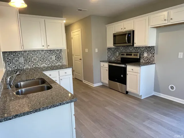 a kitchen with granite countertop a sink and a stove top oven