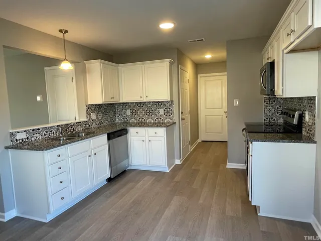 a kitchen with granite countertop white cabinets and white appliances