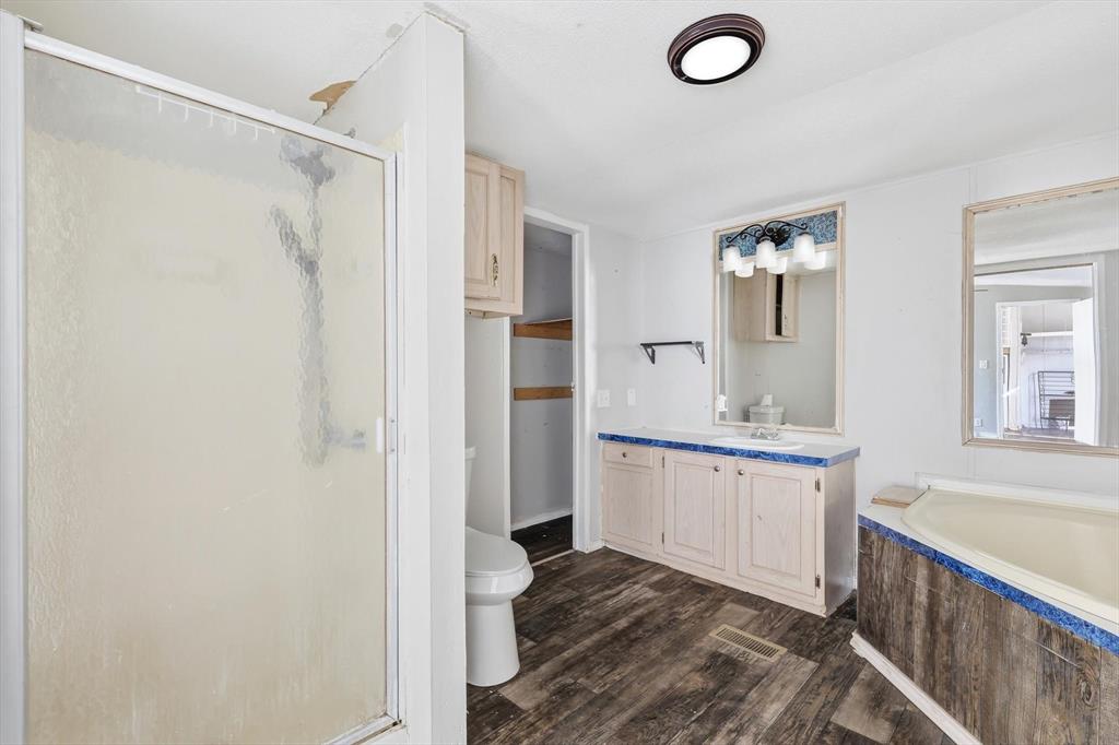 316 Summit Drive Springtown, TX 76082 - Photo 13 of 39 Bathroom featuring a shower with a translucent glass door, a corner bathtub, a vanity with a counter, and a wall-mounted mirror