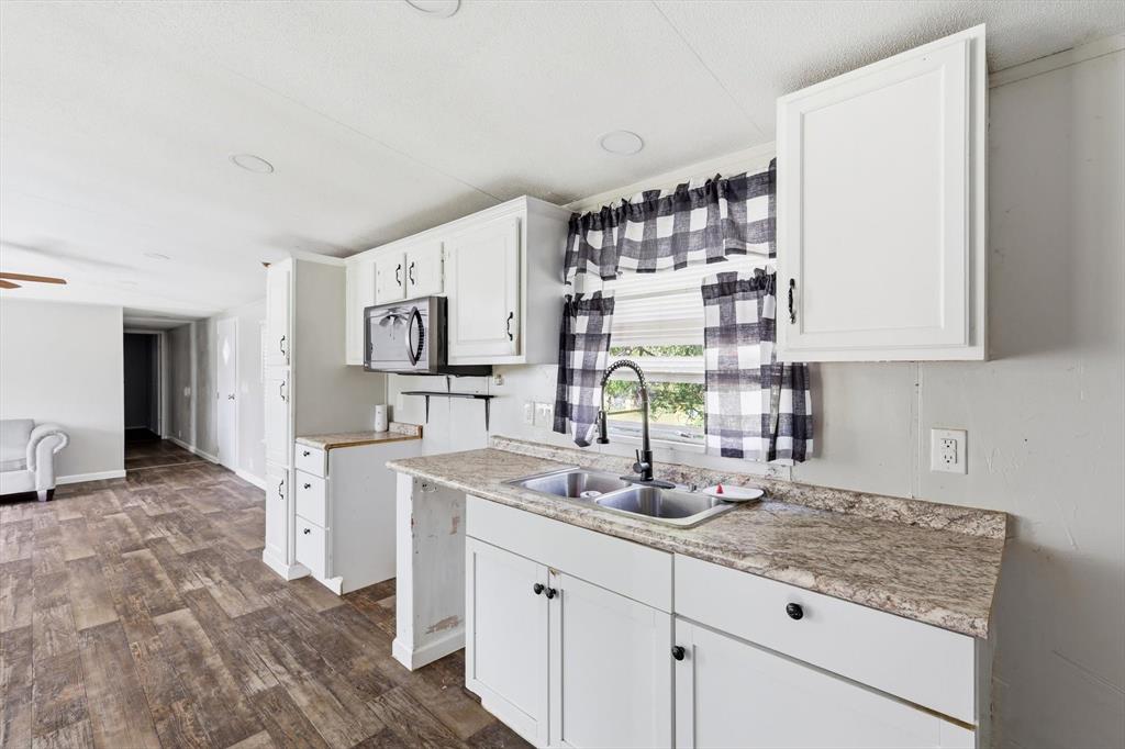 316 Summit Drive Springtown, TX 76082 - Photo 20 of 39 The kitchen features white cabinetry, a double basin sink with a black faucet, and patterned countertops