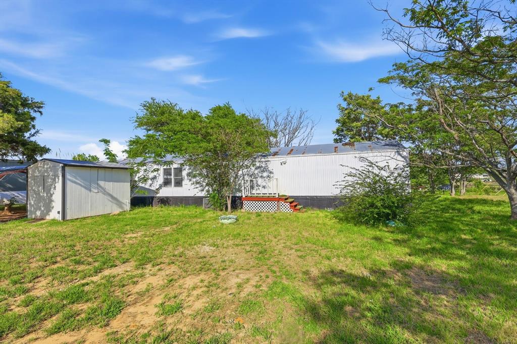 316 Summit Drive Springtown, TX 76082 - Photo 31 of 39 The property features a white exterior, a deck with red stairs, and a separate storage shed