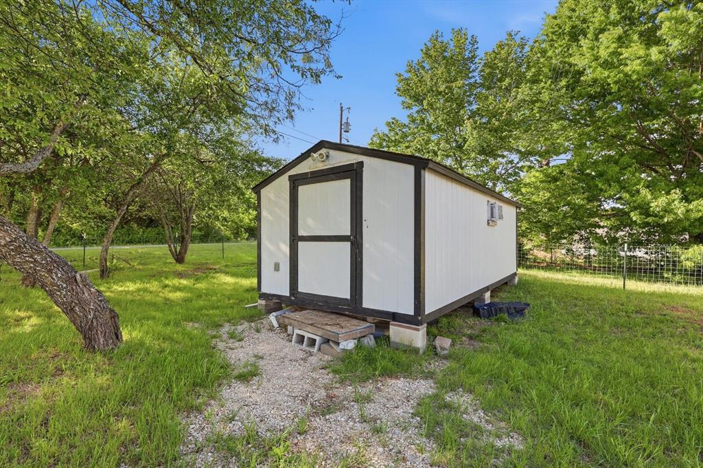 316 Summit Drive Springtown, TX 76082 - Photo 32 of 39 The property includes a white shed with black trim and a door, set on a gravel path