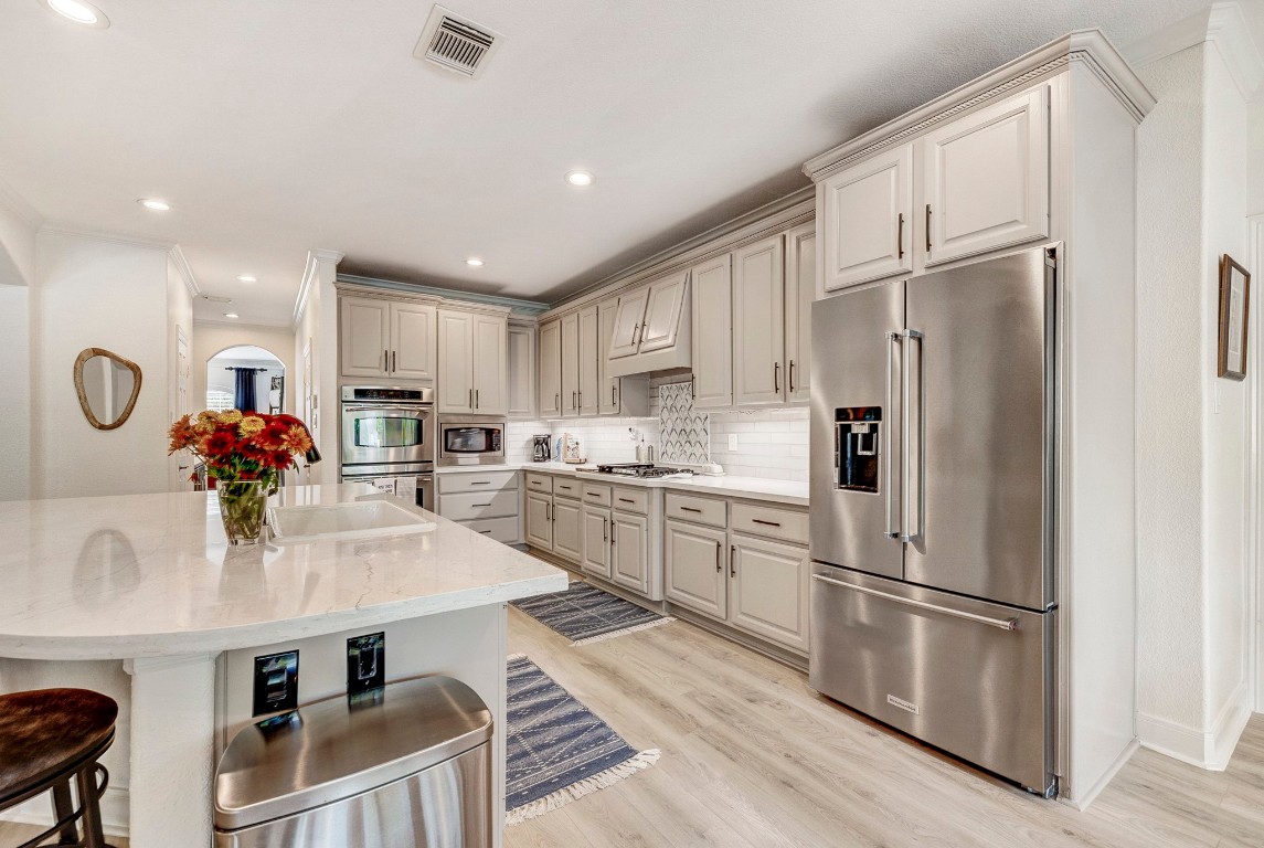 2600 Silverstone Way Conroe, TX 77304 - Photo 14 of 49 a kitchen with granite countertop a refrigerator a stove a sink dishwasher and white cabinets with wooden floor