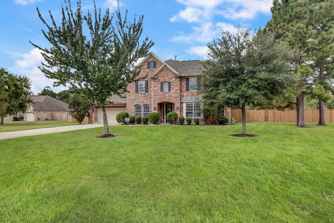 2600 Silverstone Way Conroe, TX 77304 - Photo 4 of 49 a view of a white house in front of a big yard with large trees