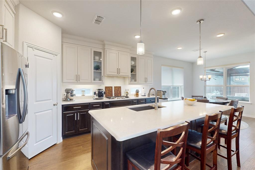 1997 Kieva Place Allen, TX 75013 - Photo 9 of 40 Kitchen featuring stainless steel appliances, a breakfast bar area, pendant lighting, dark wood finished floors, and two tone cabinets