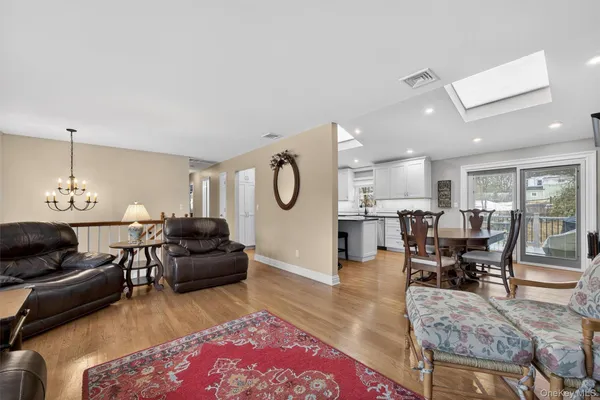 a living room with furniture a rug kitchen view and a chandelier