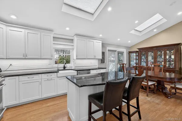 a kitchen with granite countertop a table chairs stove a sink and dishwasher with wooden floor