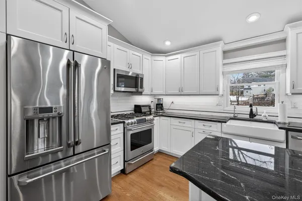 a kitchen with granite countertop a refrigerator stove and sink