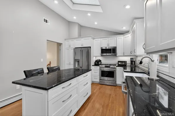 a kitchen with granite countertop a sink a counter top space stainless steel appliances and cabinets