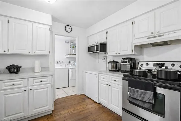 a kitchen with white cabinets and appliances