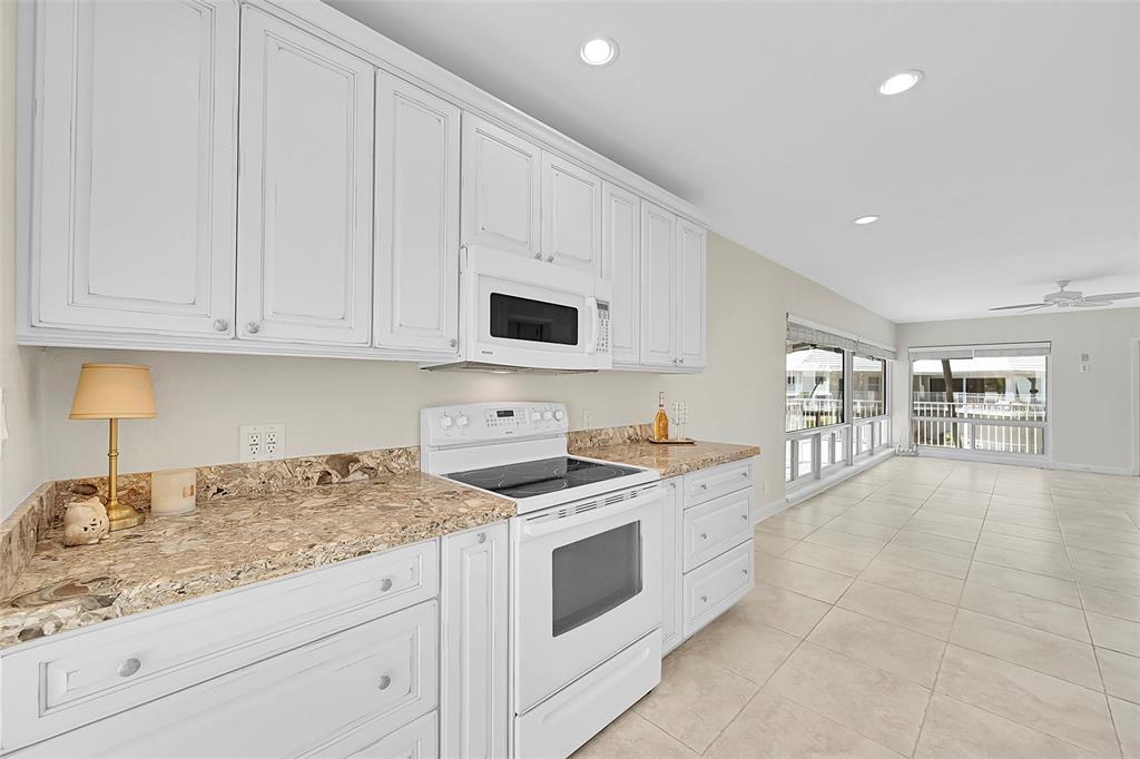 1530 South Ocean Boulevard, Unit 12 Lauderdale-by-the-Sea, FL 33062 - Photo 12 of 81 a kitchen with granite countertop white cabinets and white appliances