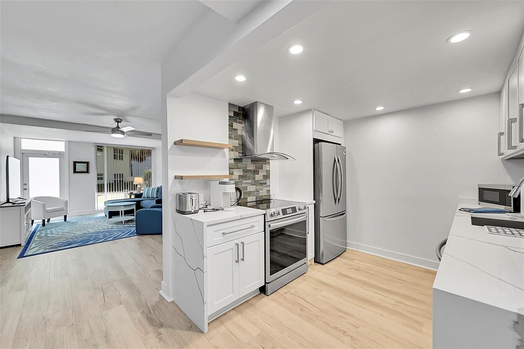 1530 South Ocean Boulevard, Unit 12 Lauderdale-by-the-Sea, FL 33062 - Photo 75 of 81 a large white kitchen with stainless steel appliances granite countertop a stove oven and a refrigerator with white cabinets