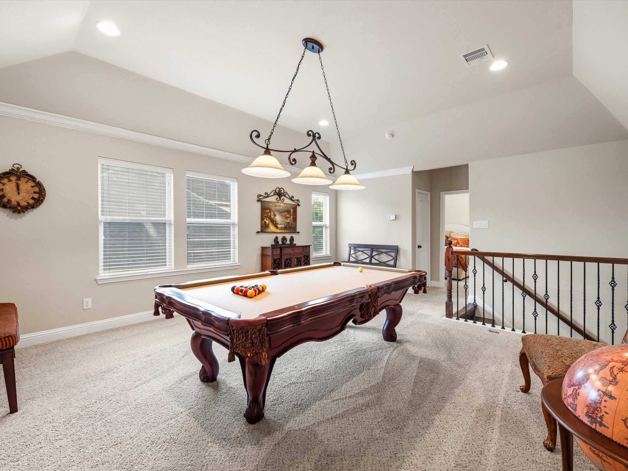 3907 Randle Ridge Court Fulshear, TX 77441 - Photo 29 of 46 This inviting game room features a classic pool table, ample natural light from two windows, and elegant lighting. The space is carpeted for comfort and has a railing overlooking the stairs, adding an open, airy feel.