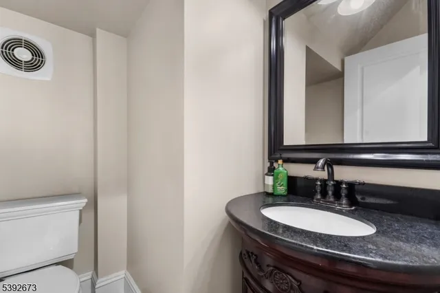 a bathroom with a granite countertop sink toilet and mirror