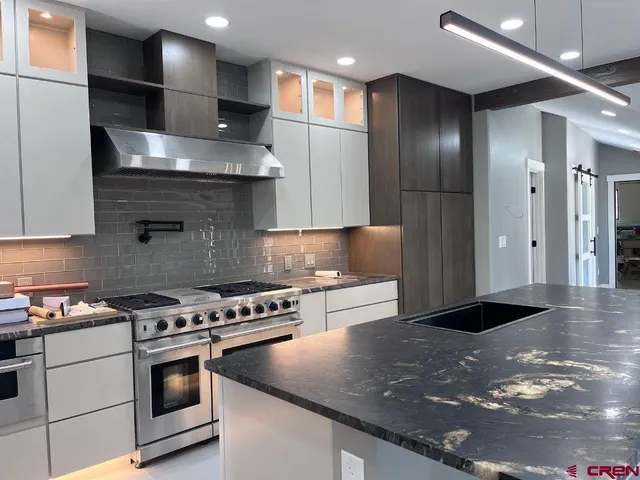 a kitchen with stainless steel appliances granite countertop a stove top oven a sink and a refrigerator