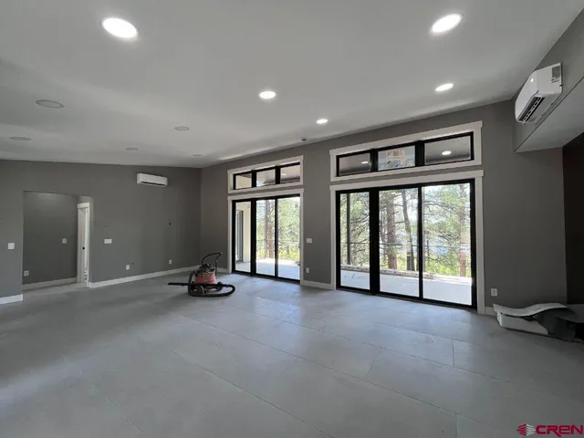 a view of an empty room with furniture and windows
