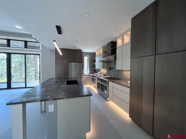 a kitchen with stainless steel appliances granite countertop a sink a stove and a refrigerator