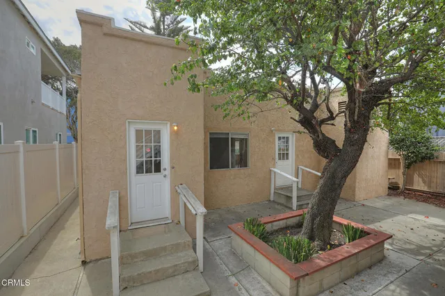 a front view of a house with a tree
