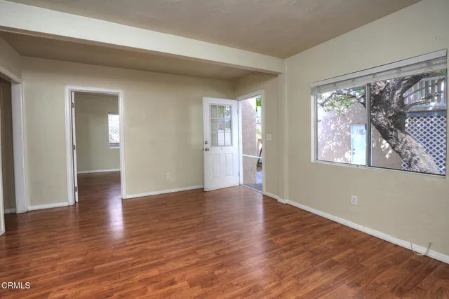 a view of an empty room with wooden floor and a window