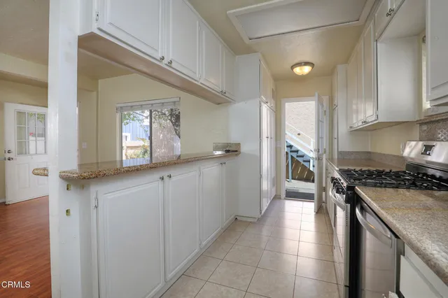 a kitchen with granite countertop a sink a stove top oven and cabinets