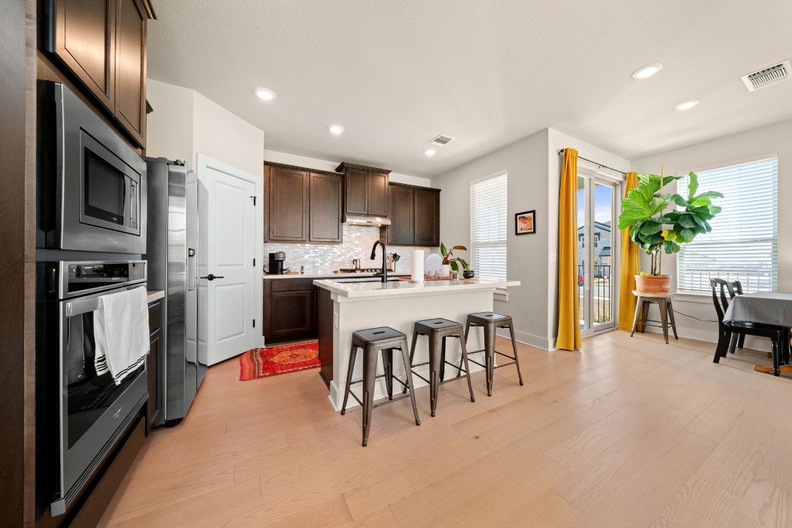 8417 Laughlin Lane Austin, TX 78744 - Photo 4 of 38 a kitchen with stainless steel appliances kitchen island granite countertop a refrigerator a stove a sink a dining table and chairs with wooden floor