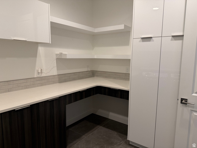 1500 Split Rock, Unit 150 Ivins, UT 84738 - Photo 15 of 18 Modern kitchen pantry featuring white upper cabinetry and dark wood-finish lower cabinetry, light-toned countertops, and an integrated subway tile backsplash