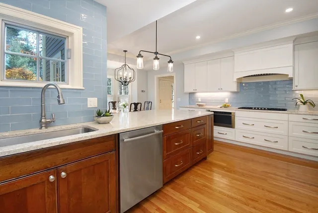 a kitchen with kitchen island granite countertop a sink a counter top space stainless steel appliances and cabinets