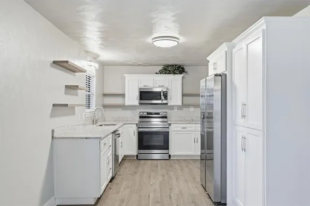 a kitchen with stainless steel appliances granite countertop a refrigerator stove and sink