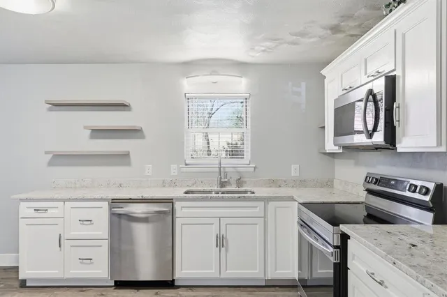 a kitchen with granite countertop white cabinets and white appliances
