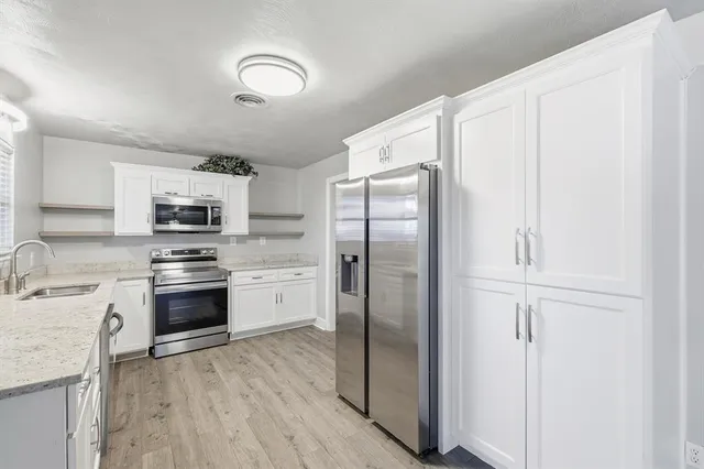 a kitchen with stainless steel appliances granite countertop a refrigerator a stove and a sink with wooden floor