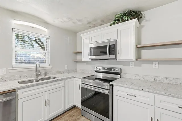 a kitchen with granite countertop white cabinets stainless steel appliances and a sink